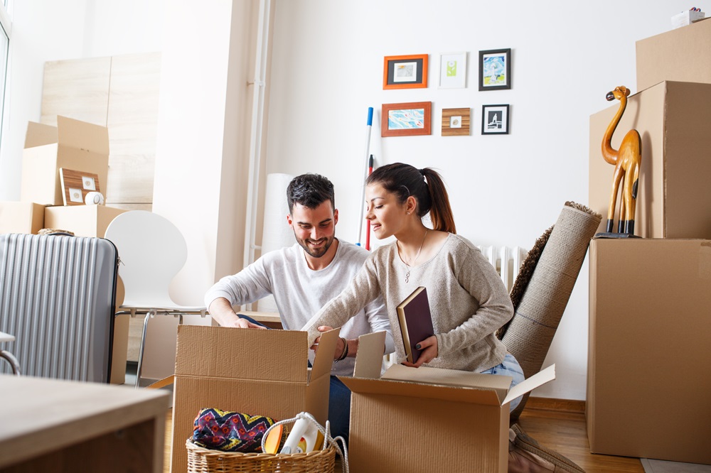 Young married couple moving into new home. They're unpacking car
